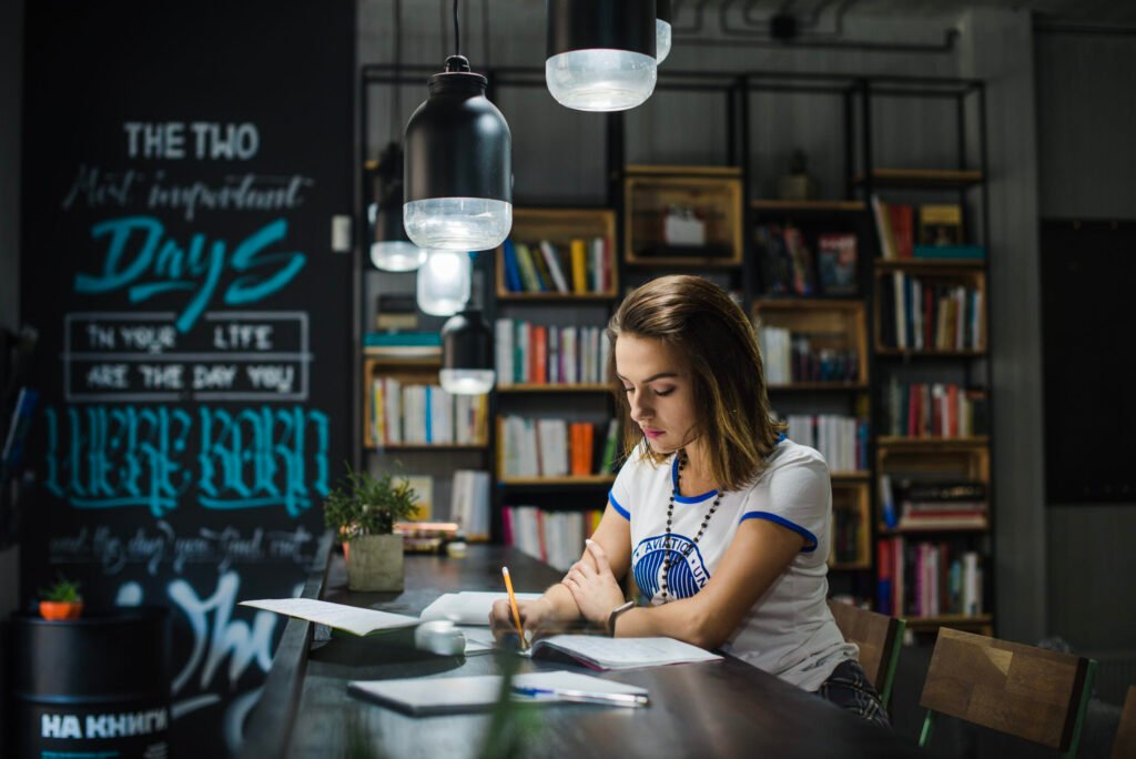 girl-sitting-table-with-notebooks-writing-scaled.jpg